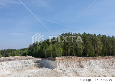 Ural Bali kaolin quarry with white clay cliffs and pine forest under blue sky 139589059