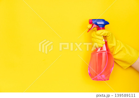 Hand in yellow glove holding cleaning spray with copy space Hand in yellow glove holding cleaning spray with copy space 139589111