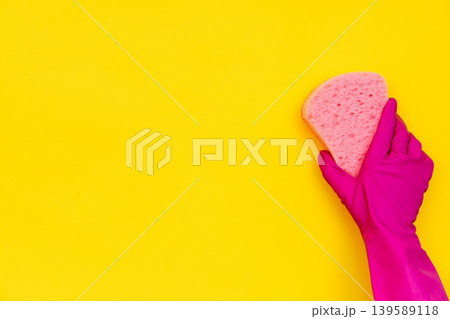 Hand in in pink rubber glove wiping yellow wall Hand in in pink rubber glove wiping yellow wall 139589118