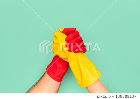 Teamwork concept with red and yellow cleaning gloves Teamwork concept with red and yellow cleaning gloves 139589137