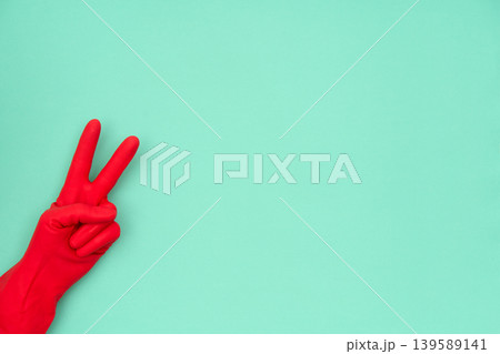 Hand in red cleaning glove showing victory peace sign Hand in red cleaning glove showing victory peace sign 139589141