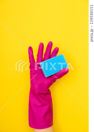 Hand in pink cleaning glove holding blue sponge Hand in pink cleaning glove holding blue sponge 139589151
