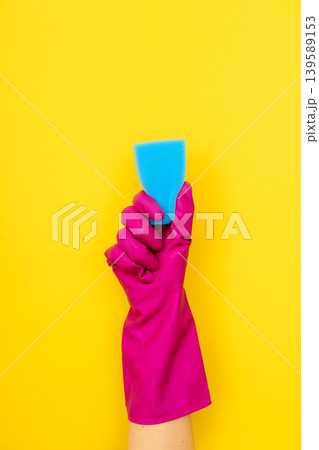 Hand in pink cleaning glove holding blue sponge Hand in pink cleaning glove holding blue sponge 139589153