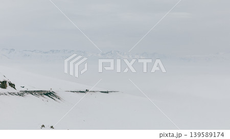 Snowy mountain road at Ala-Bel Pass with winter landscape and distant peaks 139589174