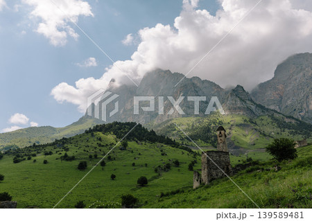 Ancient stone tower ruins in Galgai Gorge with Caucasus mountains and clouds Ancient stone tower ruins in Galgai Gorge with Caucasus mountains and clouds 139589481