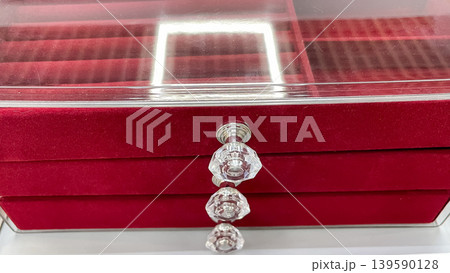Front view of a red velvet jewelry organizer with a clear acrylic lid and three drawers featuring crystal handles 139590128