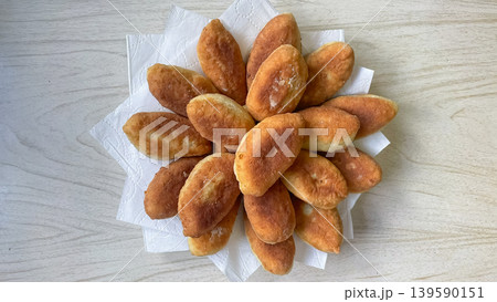 Top view of delicious golden fried pirozhki served on white napkins over a light wooden background 139590151