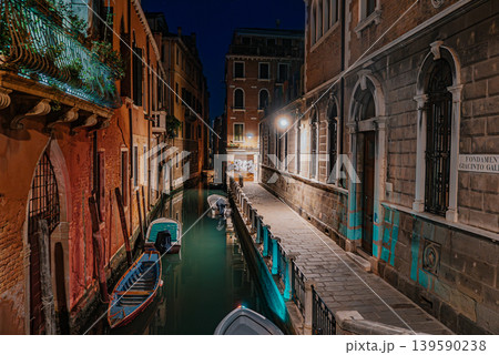 Quiet Venice canal at night with bridge, boats and glowing street lights 139590238
