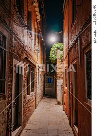 Narrow Venetian alley at night with glowing lamps and silent atmosphere Narrow Venetian alley at night with glowing lamps and silent atmosphere 139590240