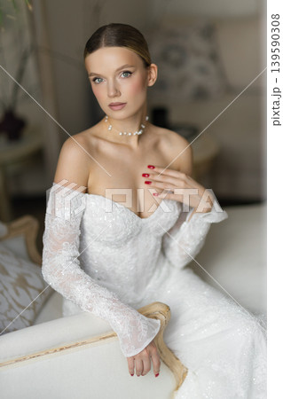 Elegant bride in white long dress posing on chaise lounge Elegant bride in white long dress posing on chaise lounge 139590308