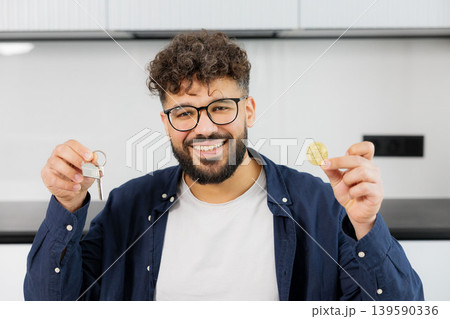 Man holding house keys and virtual cryptocurrency coin Man holding house keys and virtual cryptocurrency coin 139590336