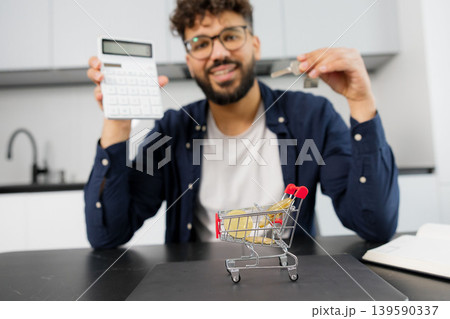 Man calculating home expenses holding house keys 139590337