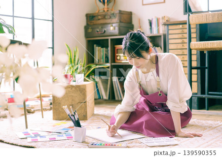リビングの床で絵を描く若い日本人女性 リビングの床で絵を描く若い日本人女性 139590355