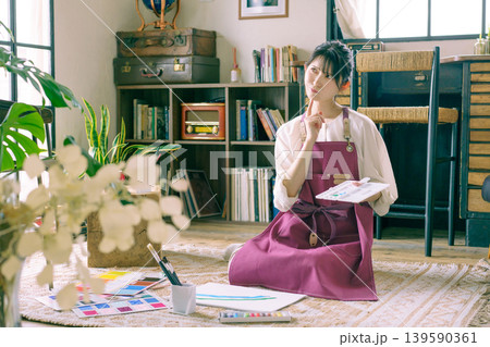 リビングの床で絵を描く困った顔の若い日本人女性 リビングの床で絵を描く困った顔の若い日本人女性 139590361