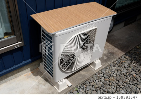 エアコン室外機。暑さ対策で上に木製板を載せている。白色機器。 139591347