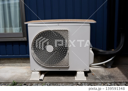 エアコン室外機。暑さ対策で上に木製板を載せている。白色機器。 139591348