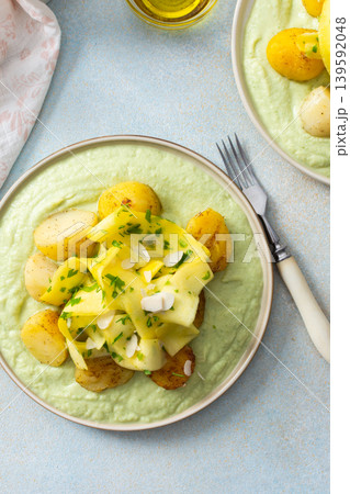 Baked potatoes are topped with fermented zucchini slices and served on a green pea sauce with broccoli for a healthy breakfast option that is hearty Baked potatoes are topped with fermented zucchini slices and served on a green pea sauce with broccoli for a healthy breakfast option that is hearty 139592048