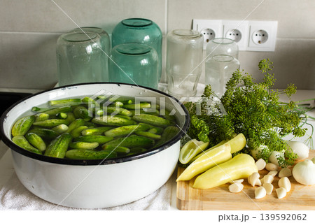 Cucumbers are being cleaned and sorted in a kitchen while glass jars are ready for canning. Ingredients are organized for preserving during the winter months ahead Cucumbers are being cleaned and sorted in a kitchen while glass jars are ready for canning. Ingredients are organized for preserving during the winter months ahead 139592062