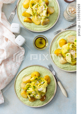 Baked potatoes are topped with slices of fermented zucchini and served alongside a green pea sauce with broccoli. This meal is prepared for a healthy breakfast Baked potatoes are topped with slices of fermented zucchini and served alongside a green pea sauce with broccoli. This meal is prepared for a healthy breakfast 139592069