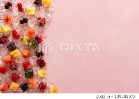 Pink background with ice cubes with frozen berries and fruits and mint Pink background with ice cubes with frozen berries and fruits and mint 139592078