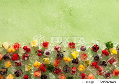 Green background with ice cubes with frozen berries and fruits and mint Green background with ice cubes with frozen berries and fruits and mint 139592089