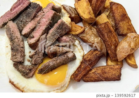 Juicy sliced beef steak served with roasted potatoes and sunny side egg in hearty meal presentation 139592617