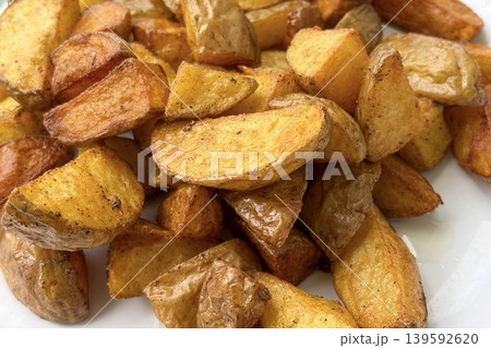 Delicious homemade fried potato chunks with crispy outer texture and warm golden roasted appearance on plate 139592620