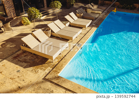 Swimming pool with empty lounge chairs at luxury resort on sunny day Swimming pool with empty lounge chairs at luxury resort on sunny day 139592744