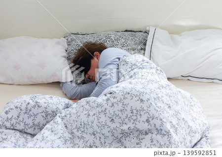 A 50-year-old woman is comfortably sleeping in her bed with a sleep mask on. She is wrapped in a soft blanket, resting peacefully in a serene bedroom setting A 50-year-old woman is comfortably sleeping in her bed with a sleep mask on. She is wrapped in a soft blanket, resting peacefully in a serene bedroom setting 139592851