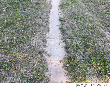 A narrow dirt path through a field with overgrown grass in places, the natural texture of a walking trail 139592974