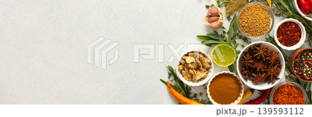 A mix of dried herbs and spices laid out on a gray background, highlighting natural flavors and culinary essentials, top view and copy space, banner 139593112