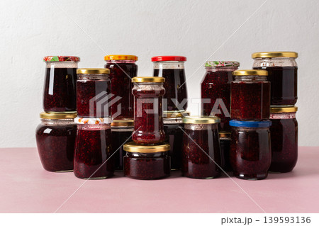 Jars filled with homemade strawberry and raspberry jam are neatly arranged on a table, ready for winter storage and use in meals and treats during the chilly season Jars filled with homemade strawberry and raspberry jam are neatly arranged on a table, ready for winter storage and use in meals and treats during the chilly season 139593136