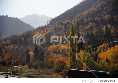 Cable car gondolas moving over autumn mountain forest in Shymbulak, Kazakhstan. Cable car gondolas moving over autumn mountain forest in Shymbulak, Kazakhstan. 139593454