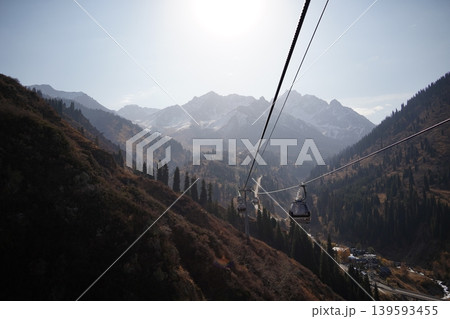 Cable car gondolas moving over autumn mountain forest in Shymbulak, Kazakhstan. Cable car gondolas moving over autumn mountain forest in Shymbulak, Kazakhstan. 139593455