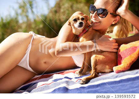 Woman, happy and relaxing on beach and sunbathing with dog, vacation and travel to Hawaii. Female person, resting and tanning on sand and peaceful by water, nature and wellness by ocean and animal 139593572