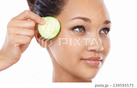Woman, face and cucumber by eyes in skincare, beauty or facial and spa treatment against a white studio background. Closeup of female person or model with natural organic vegetables for wellness Woman, face and cucumber by eyes in skincare, beauty or facial and spa treatment against a white studio background. Closeup of female person or model with natural organic vegetables for wellness 139593573
