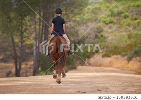 Equestrian, trail and riding a horse in nature on adventure and journey in countryside. Ranch, animal and back of rider outdoor with pet on path in forest or woods for hobby on farm in summer Equestrian, trail and riding a horse in nature on adventure and journey in countryside. Ranch, animal and back of rider outdoor with pet on path in forest or woods for hobby on farm in summer 139593616