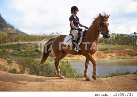 Equestrian, woman and riding a horse in nature on adventure and journey in countryside. Ranch, animal and rider outdoor with hobby, sport or walking a pet on farm with girl in summer at river Equestrian, woman and riding a horse in nature on adventure and journey in countryside. Ranch, animal and rider outdoor with hobby, sport or walking a pet on farm with girl in summer at river 139593735