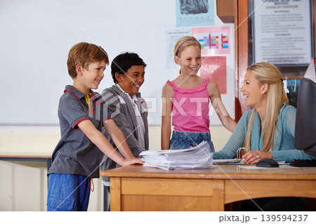 Teacher, students or happy kids talking in classroom for education, learning or tutoring at school. Woman, mentor or educator helping a group of young children with paperwork for studying in class Teacher, students or happy kids talking in classroom for education, learning or tutoring at school. Woman, mentor or educator helping a group of young children with paperwork for studying in class 139594237