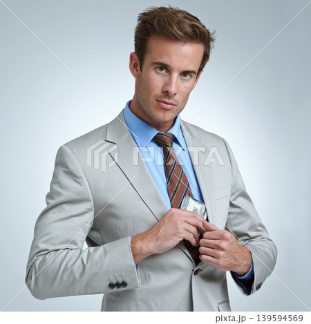 Businessman, portrait and cash in studio for money laundering, white collar crime or investment. Finance, entrepreneur or person with stealing and fraud at corporate job or company on gray background 139594569