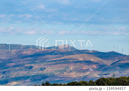 Wind turbines line the hills under a blue sky 139594857