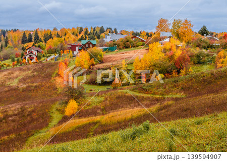Autumn landscape with colorful foliage and small village in the distance Autumn landscape with colorful foliage and small village in the distance 139594907
