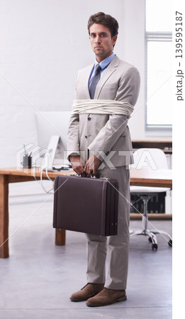 Portrait of businessman in workplace tied up in rope with depression, control and sad in law firm. Serious attorney, lawyer or legal consultant bound in office, corporate hostage with bag and stress. 139595187