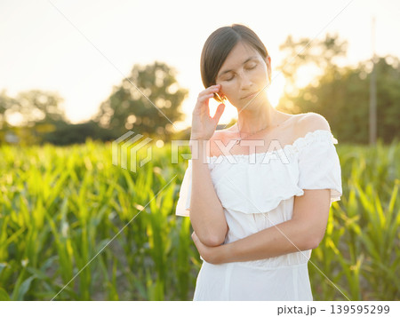 Woman in white dress walking through sunset field in Croatia Woman in white dress walking through sunset field in Croatia 139595299