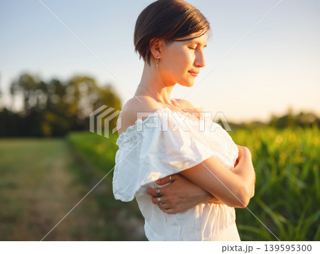 Woman in white dress walking through sunset field in Croatia Woman in white dress walking through sunset field in Croatia 139595300