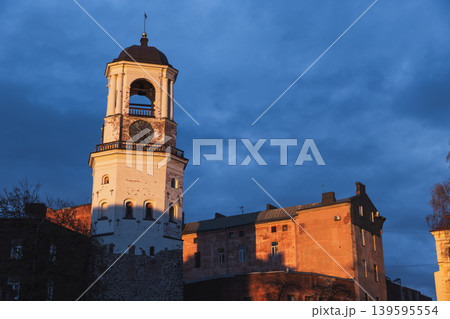 A historic clock tower of Vyborg and adjacent old town buildings glow in warm sunset A historic clock tower of Vyborg and adjacent old town buildings glow in warm sunset 139595554