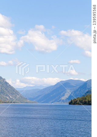 A tranquil mountain lake landscape featuring deep blue water, forested shores 139595568