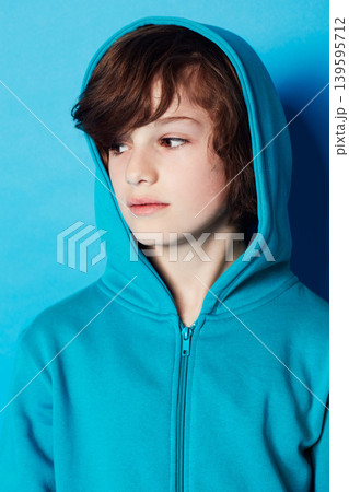 Studio, fashion or young kid in hoodie, trendy apparel or stylish outfit isolated on blue background. Cotton fabric, adolescent boy and youth child with clothes, casual outfit and looking at style Studio, fashion or young kid in hoodie, trendy apparel or stylish outfit isolated on blue background. Cotton fabric, adolescent boy and youth child with clothes, casual outfit and looking at style 139595712