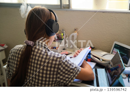 Teenage girl in headphones at the table Teenage girl in headphones at the table 139596742