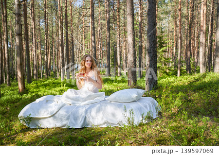 Young woman has breakfast in bed in a summer forest 139597069